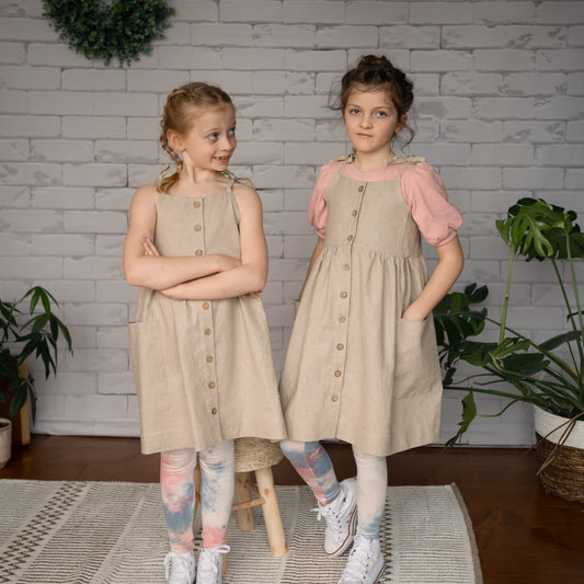 two kids wearing linen pocket dresses with t-shirting under