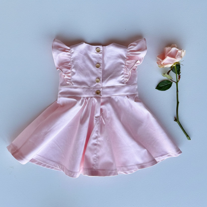 Pink dress with ruffled sleeves and a rose on a light blue background