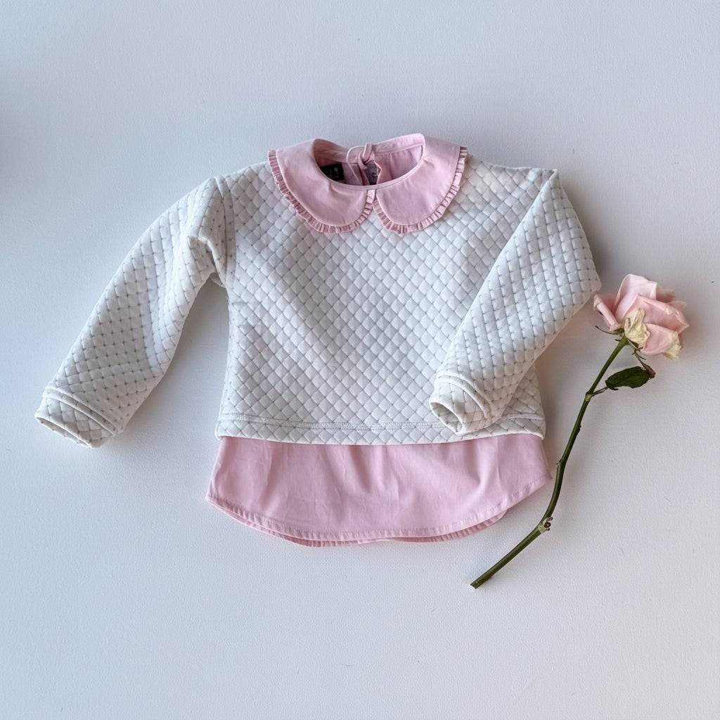 White quilted baby sweater with pink collar and trim on a light gray background