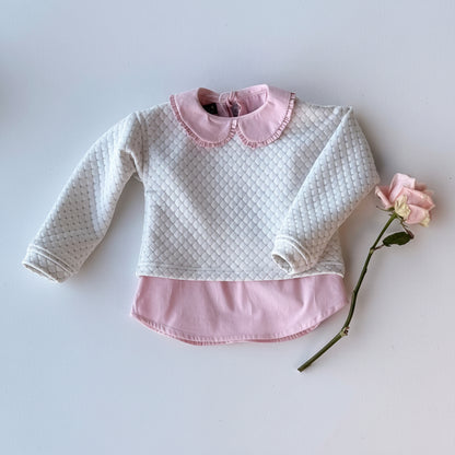 White quilted baby sweater with pink collar and trim on a light gray background