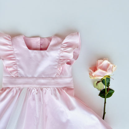 Pink dress with ruffled sleeves and a single pink rose on a light blue background