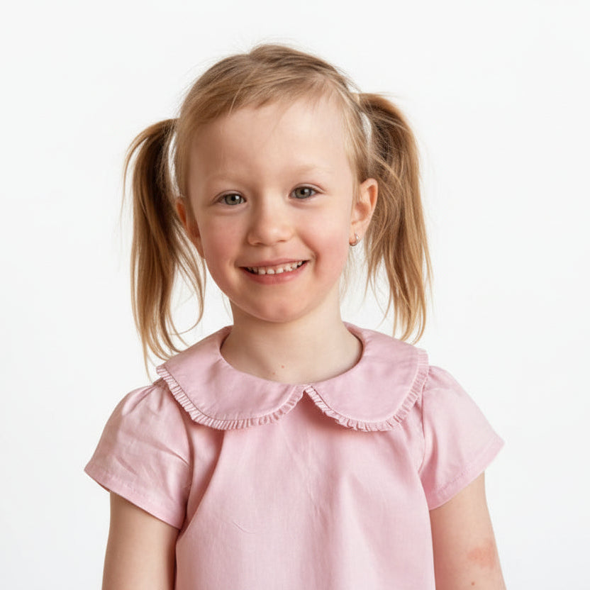 Young girl in a pink dress with a stone wall background