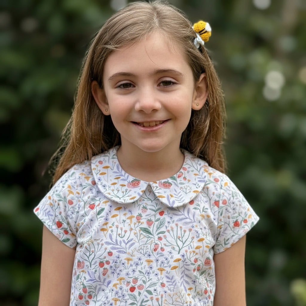 Young girl wearing a floral dress with a blurred green background