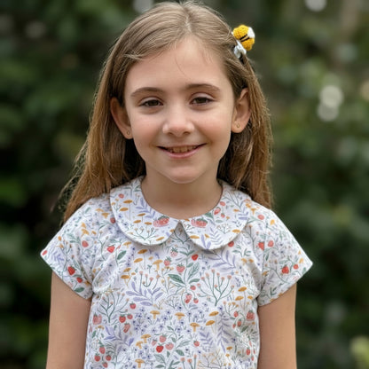 Young girl wearing a floral dress with a blurred green background